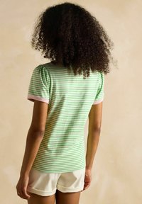 Roheline ja valge triibuline t-särk lühikeste puffvarrukatega ja roosa äärisega, valmistatud pehmest kangast, koos valgete lühikeste pükstega.