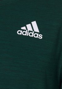White Adidas logo with three stripes on dark green textured fabric background.