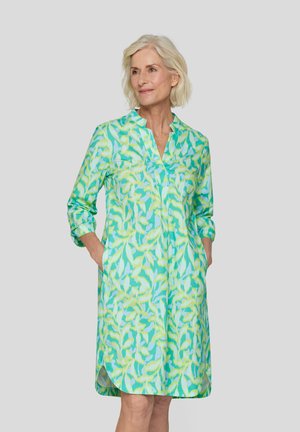Knopfkleid im grün-gelben Blumenmuster, mit langen Ärmeln und seitlichen Taschen. Leichter Stoff mit lockerer Passform.