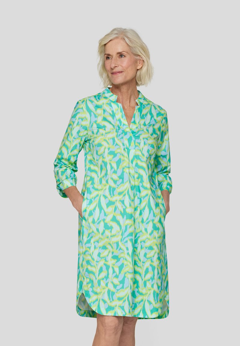 Knopfkleid im grün-gelben Blumenmuster, mit langen Ärmeln und seitlichen Taschen. Leichter Stoff mit lockerer Passform.