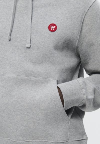 Grauer Hoodie mit einer Fronttasche, Kordelzugkapuze und einem kleinen roten runden Logo. Weicher Stoff und lockere Passform, ideal für Freizeitkleidung.