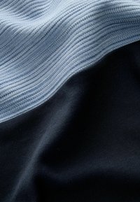 Strikket stof med en vandret gradient i lys blå og mørk marine, med ribbet tekstur øverst og glat finish nedenfor.