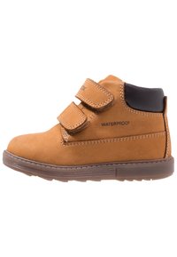 Wasserfeste Knöchelstiefel aus Wildleder, ausgestattet mit zwei Klettverschlussriemen, brauner Gummisohle und kontrastierendem schwarzen Absatz.