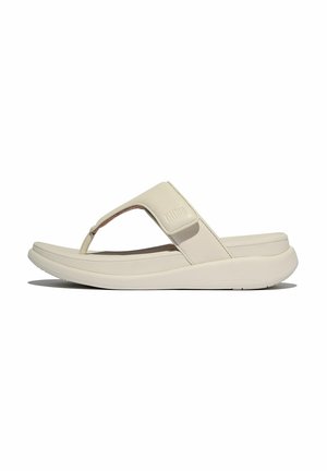 Des sandales tongs beige clair avec une sangle texturée et mate et une semelle coussinée, présentant un design simple et une forme arrondie.