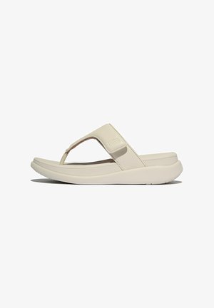 Des sandales tongs beige clair avec une sangle texturée et mate et une semelle coussinée, présentant un design simple et une forme arrondie.