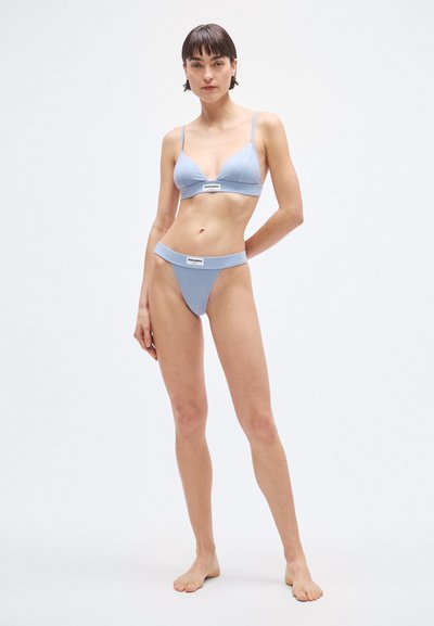 Conjunto de bikini azul claro hecho de tela suave; cuenta con un bralette triangular con tirantes delgados y una tanga de tiro bajo con una banda con logo.