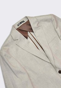Ljusbeige linneskjorta med slagkrage, en-knappsstängning och en brun foder med subtila ränder. Regular fit-design.