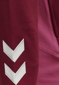 Maroen stof met twee witte chevronstrepen en gestructureerde roze stof met een gestikte naad.