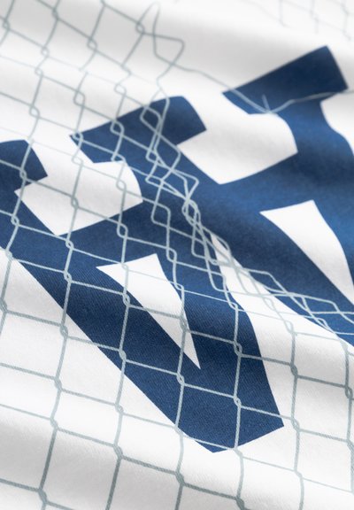 Λευκό ύφασμα με μεγάλο μπλε σχέδιο γεωμετρικών σχημάτων, επικαλυμμένο με ανοιχτό μπλε μοτίβο πλέγματος.
