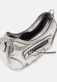 Piccola borsa d'argento con texture a coccodrillo, tasca frontale con zip, interno nero e chiusura a zip visibile su sfondo bianco.