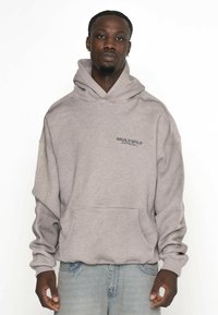 Grå hoodie i bomullsblandning med en framficka och dragsko i huvan, med en liten "MULTIPLY APPAREL" logo på bröstet.