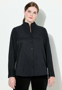 Zwarte blouse met lange mouwen en een staande kraag, sluiting met knopen aan de voorkant, zachte textuur en een rechte snit, geschikt voor casual of formele gelegenheden.