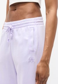 Παντελόνι φόρμας χρώματος λεβάντας φτιαγμένο από απαλό υλικό. Διαθέτει ριμπ ζώνη μέσης, ρυθμιζόμενο κορδόνι, πλαϊνή τσέπη και κεντημένο λογότυπο.