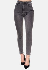 Jeans ajustados en algodón denim gris oscuro, con una cintura alta, diseño de cinco bolsillos y una textura suave, combinados con zapatos de tacón altos negros.