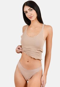 Beiges Loungewear-Set bestehend aus einem Tanktop und passenden Unterhosen, beide mit Spitzendetails und einer weichen, glatten Textur. Das Tanktop hat einen gewellten Saum.