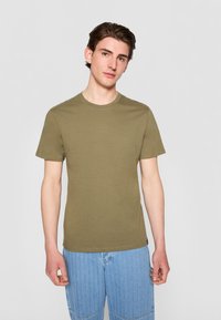 Oliven grønn bomull t-skjorte med rund hals og korte ermer, med et enkelt design og en noe tettsittende fasong.