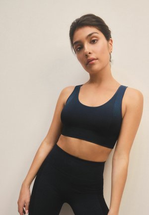 Black athletic crop top with textured design and wide straps, paired with matching high-waisted leggings, highlighting a seamless look.