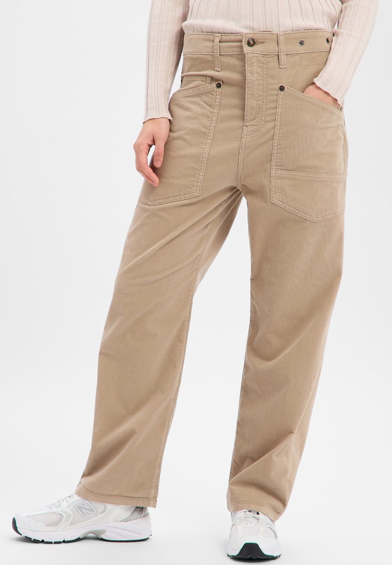 Beige wide-leg pants with a high waist, two front pockets, and contrasting stitching. Paired with white sneakers.