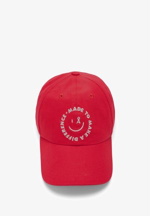 Red baseball cap made of cotton, featuring a white embroidered smiley face and text "MADE TO MAKE A DIFFERENCE" around it.