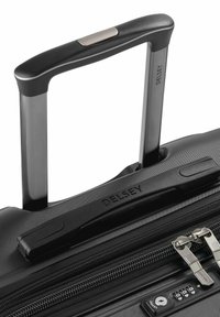 Schwarzer Hartschalenkoffer mit strukturiertem Oberflächen, teleskopischem Griff und einem Reißverschlussverschluss mit integriertem Zahlenschloss.