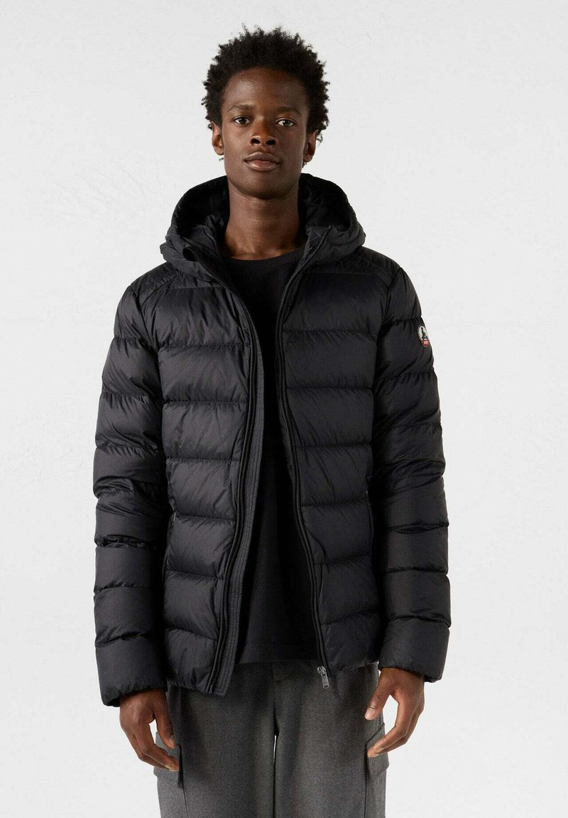 Zwarte pufferjas met capuchon, voorzien van doorgestikte segmenten, een ritssluiting aan de voorkant en een logopatch op de linker schouder. Gladde, glanzende stof.