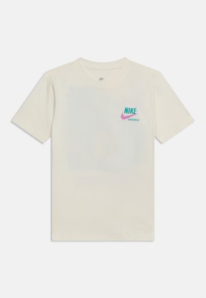 Off-white kortærmet Nike T-shirt med teal og pink "Nike Sportswear" logo på venstre bryst, vist på en ensfarvet baggrund.