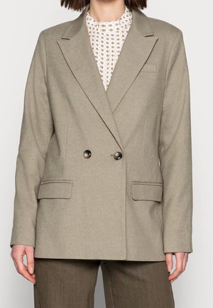 Blazer beige à double boutonnage avec revers, deux poches avant et boutons marron ; texture lisse et coupe ajustée.