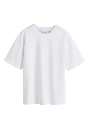 Hvid bomulds T-shirt med korte ærmer og rund hals. Bagfra ses en afslappet pasform og glat tekstur. Båret med olivenfarvede cargo-bukser.