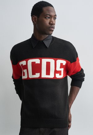 Pulôver tricotado em preto e vermelho com grande texto branco "GCDS", gola e punhos canelados, com riscas horizontais em contraste.