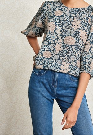 Blomstermønstret top i marineblå og blush toner, med rund halsudskæring og korte ærmer. Sammen med klassiske blå denimjeans.