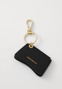 Porte-clés en cuir noir avec une finition texturée. Équipé d'un clip en métal doré et d'un anneau, avec le logo "COCCINELLE" embossé en doré.