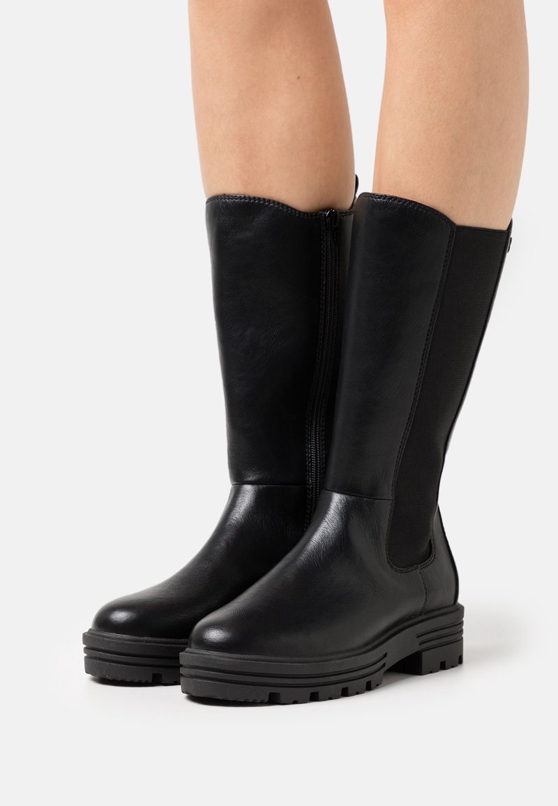 Bottes hautes jusqu'au genou en cuir noir avec une texture lisse, fermeture éclair latérale et panneau élastique contrastant. Semelle en caoutchouc épaisse avec adhérence.