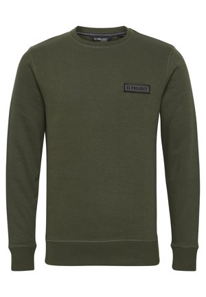 Olivno zelen pulover iz mehkega materiala s okroglim izrezom, dolgimi rokavi in rebrastimi manšetami. Ima črn pravokoten zank na prsih.