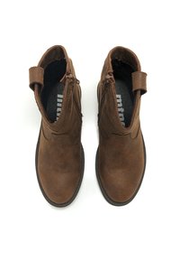 Botines de ante marrón con textura suave, que cuentan con cremalleras laterales y una tira de agarre, puntera redonda y suela de goma plana.