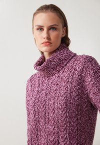 Pleteni pulover s turtleneck iz strukturirane slivove preje z vzorec kabel. Ima širok, zliven ovratnik in sproščen kroj.