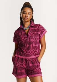 Polo s krátkým rukávem, růžový vzorovaný a odpovídající šortky vyrobené z texturované látky, s dekorativním designem mušlí a detailním třásňovým lemem.