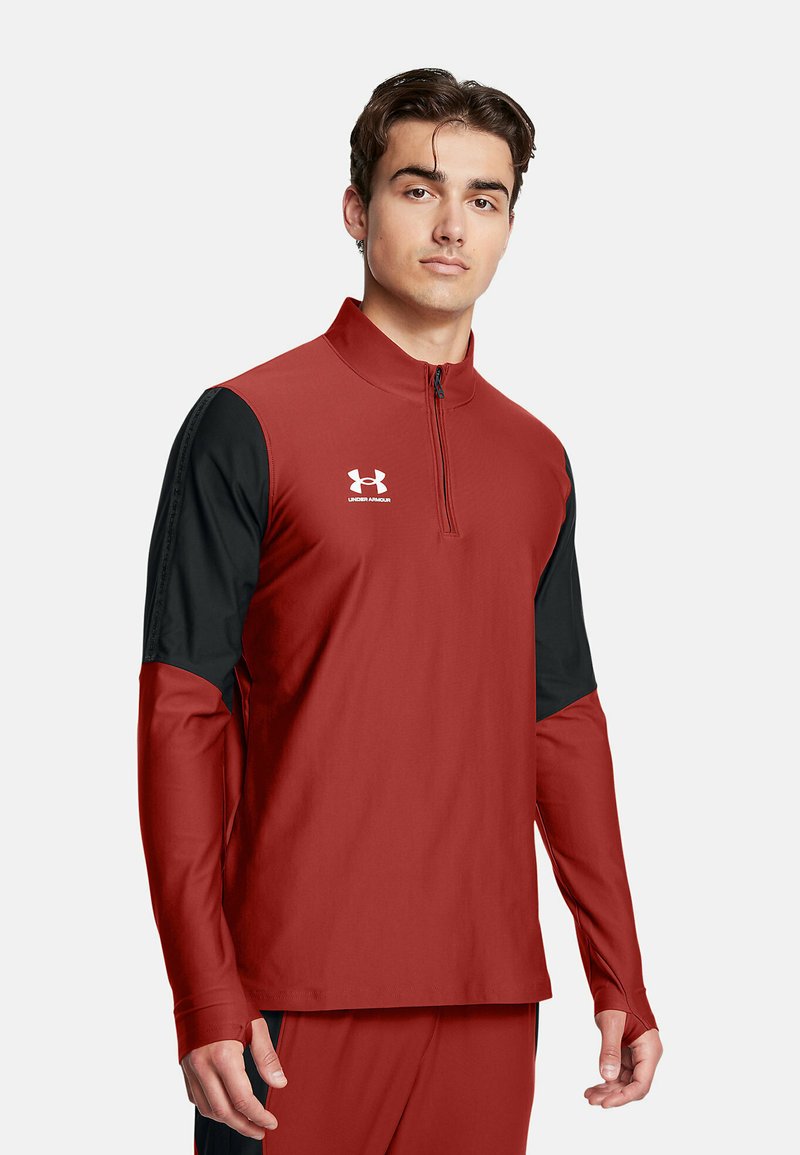 Červený a čierny športový pulóver s vysokým golierom, štvrtinovým zipsom a dlhými rukávmi. Obsahuje logo Under Armour na hrudi. Vyrobený z hladkej tkaniny.