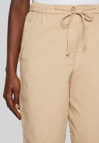 Beige, lichtgewicht katoenen broeken met een elastische tailleband, trekkoord en zijzakken. Heeft een gladde textuur en een rechte snit.