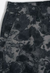 Ciemnoszary materiał dżinsowy z marmurkowym wzorem, z pasem, kieszeniami i metalowymi guzikami. Gładka tekstura z delikatnym połyskiem.