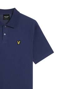 Marineblå polo shirt i tekstureret materiale med en foldet krave, tre-knaps placket og et gult broderet ørnerlogo på brystet.