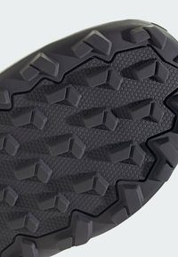 Semelle de chaussure en caoutchouc noir avec motif de bande de roulement hexagonal et crampons angulaires surélevés pour une meilleure traction et durabilité.