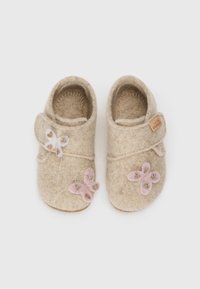 Chaussons en feutre beiges avec une bride à velcro. Agrémentés d'appliqués en forme de papillon blancs et roses et de légers détails de couture.