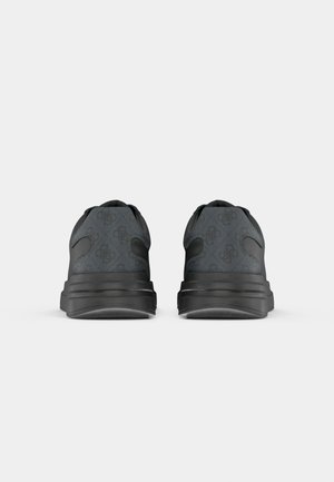 Paire de baskets noires vues de dos avec une semelle épaisse et un motif subtil sur la tige en tissu sur fond gris uni.