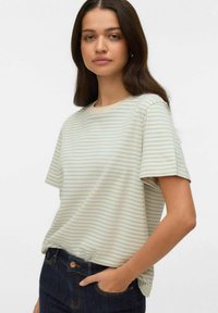 Randig t-shirt i ljuskräm och mjuk blå färg, med korta �ärmar och rund halsringning, kombinerad med mörka jeans i denim.