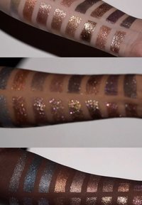 Stalen van verschillende glitteroogschaduws op twee armen; de tinten omvatten brons, goud, paars en zilver, die schittering en textuur laten zien.