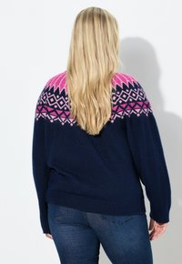 Maglione lavorato a maglia blu navy con una balza geometrica rosa e nera. Design ampio con polsini e orlo a coste.