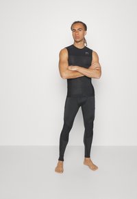 Black athletic bodysuit featuring sleeveless design and tapered legging. Smooth texture with subtle panel detailing, fitted for performance.