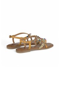 Tan leren sandalen met decoratieve kraalbandjes, een platte zool en gespsluiting. Bevat meerkleurige versieringen en een ingeweven ontwerp.