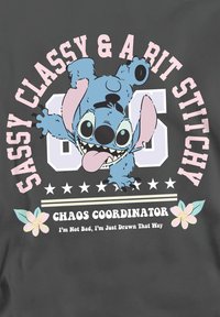 Gray fabric featuring a graphic of a blue cartoon character, with pink text reading "Sassy Classy & A Bit Stitchy" and floral designs.