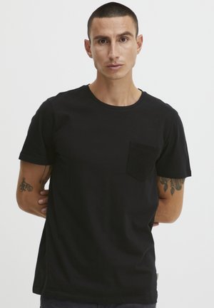 Sort bomulds T-shirt med rund hals og korte ærmer, der har en struktureret sort lomme på venstre bryst. Glat tekstur, afslappet pasform.